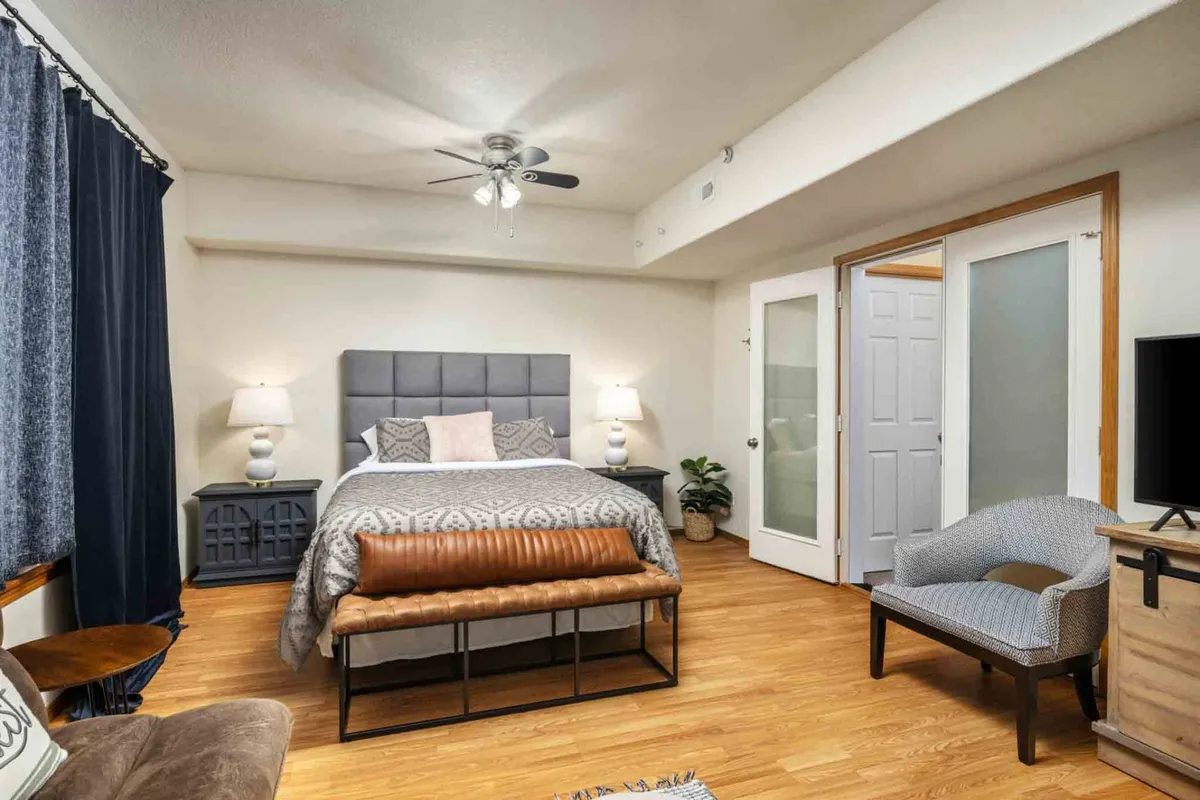A cozy bedroom with a large bed, nightstands, an armchair, and decorative pillows. This tranquil interior provides a comfortable, restful retreat for family members of all ages after a day of activities and adventures.