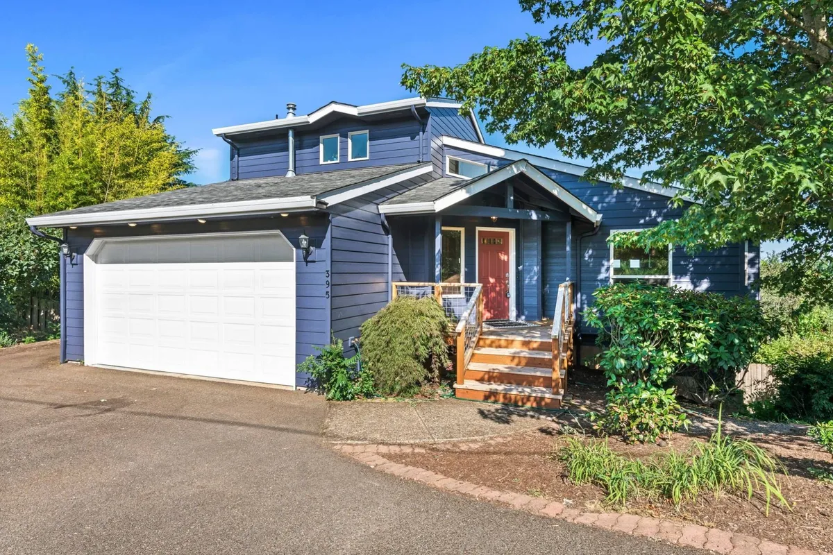 A welcoming exterior view of Dogwood Villa, featuring the front entrance, a neatly landscaped yard, and the garage. The home sits amidst greenery, suggesting a safe and inviting space for arriving guests and their pets. The yard is open and spacious, ideal for outdoor activities and supervised play with pets.