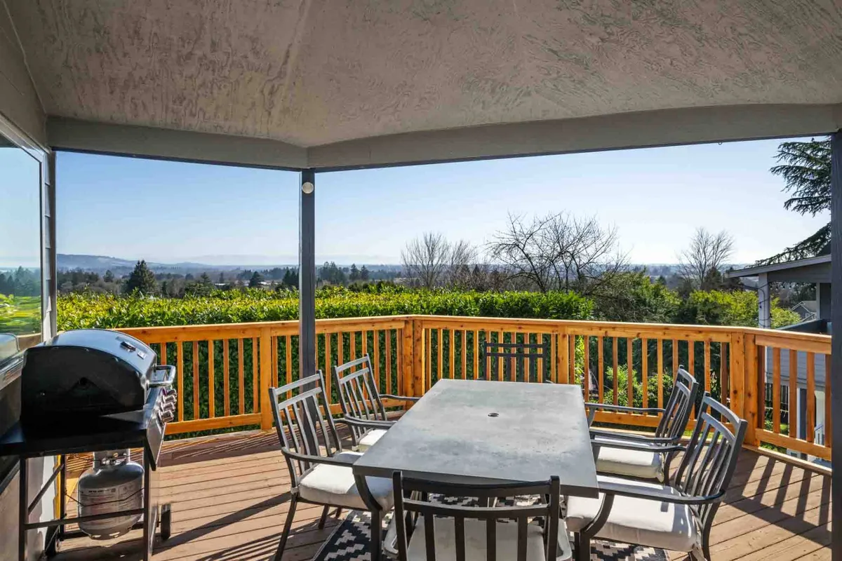 An outdoor dining table and grill set on a spacious deck, overlooking scenic natural vistas. The area is designed for gatherings, al fresco meals, and taking in breathtaking sunsets or starlit evenings.