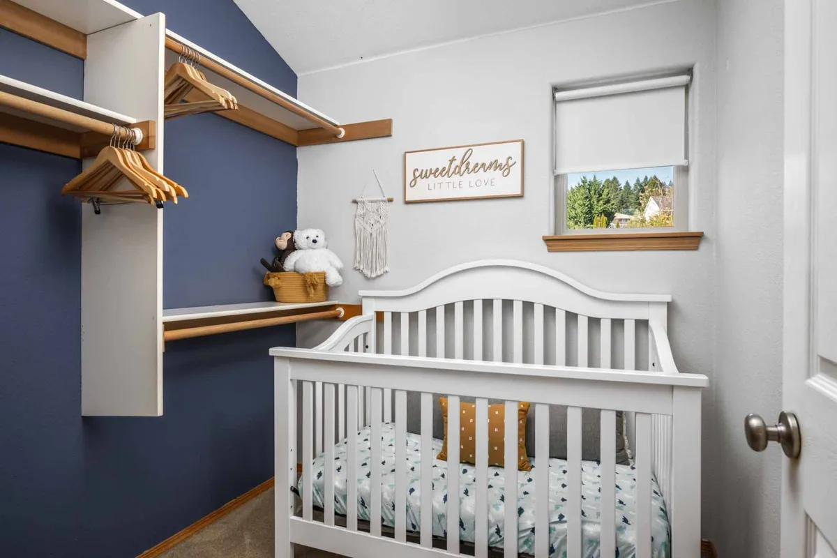 A cozy, dedicated nursery with a crib, whimsical wall decor, and plush stuffed animals. The nursery feels safe and welcoming, ideal for families with young children.